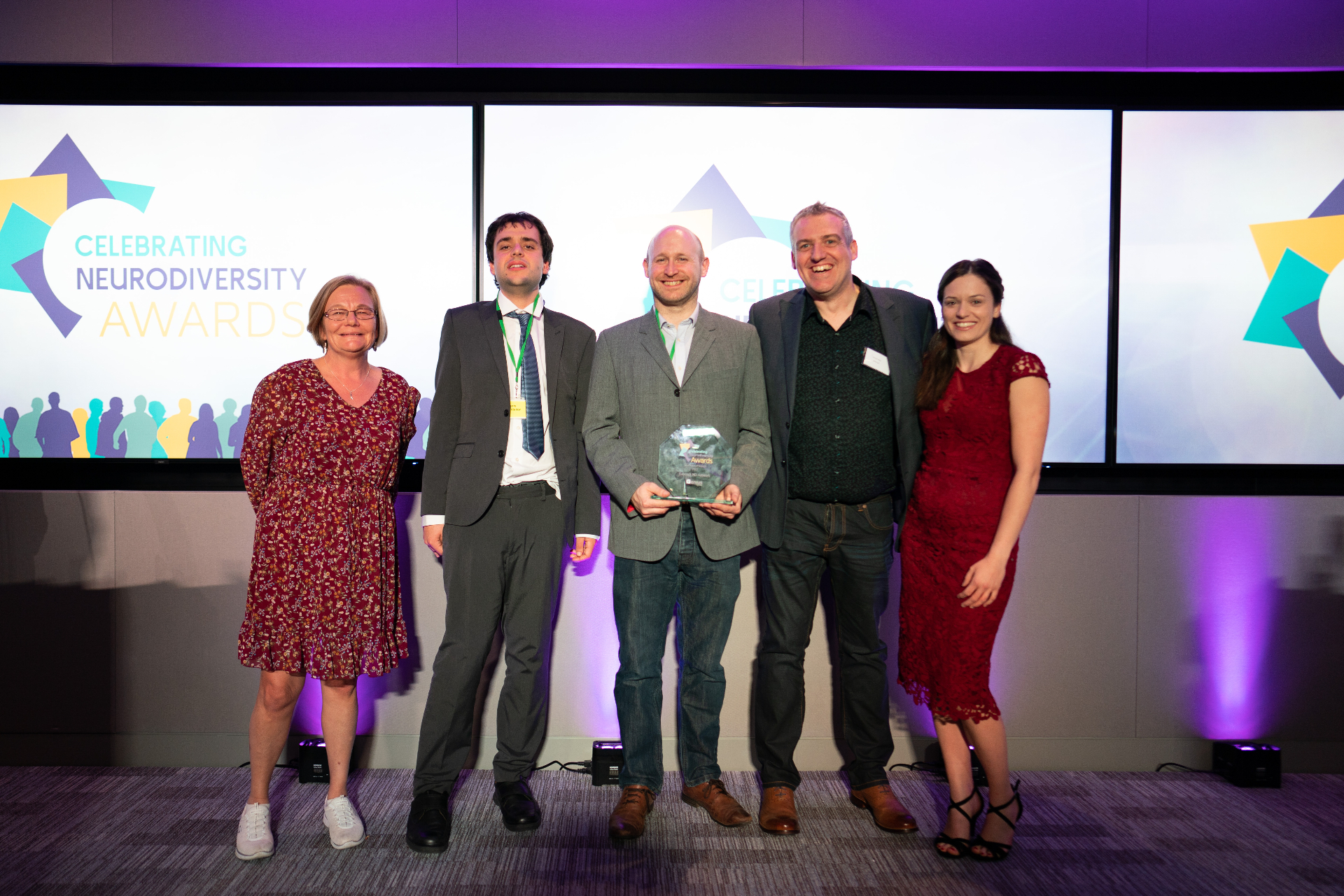 Wayne Kelly on stage with the winning team receiving the Celebrating Neurodiversity Award trophy